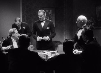 Movie still from “Grand Hotel” (1932), directed by Edmund Goulding – A black and white photo of a group of men sitting around a table; Medium shot, Over the shoulder angle