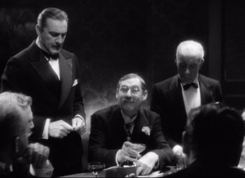 Movie still from “Grand Hotel” (1932), directed by Edmund Goulding – A group of men sitting around a table; Medium shot, Over the shoulder angle