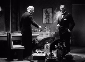 Movie still from “Grand Hotel” (1932), directed by Edmund Goulding – Two men standing in a living room smoking and drinking; Medium shot, Low angle