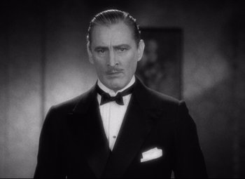 Movie still from “Grand Hotel” (1932), directed by Edmund Goulding – A man in a suit and bow tie in front of a painting; Close Up shot, Low angle