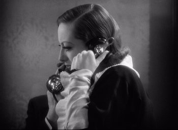 Movie still from “Grand Hotel” (1932), directed by Edmund Goulding – A woman talking on a phone while wearing a white dress; Close Up shot, High angle