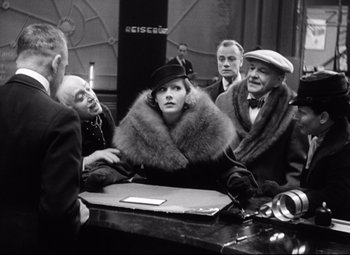 Movie still from “Grand Hotel” (1932), directed by Edmund Goulding – A group of people sitting around a table; Medium shot, Over the shoulder angle