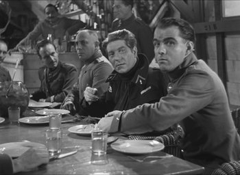 Movie still from “The Grand Illusion” (1937), directed by Jean Renoir – A black and white photo of men sitting at a dinner table; Medium shot, Over the shoulder angle