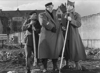 Movie still from “The Grand Illusion” (1937), directed by Jean Renoir – A group of men standing next to each other holding shovels; Medium shot, Over the shoulder angle