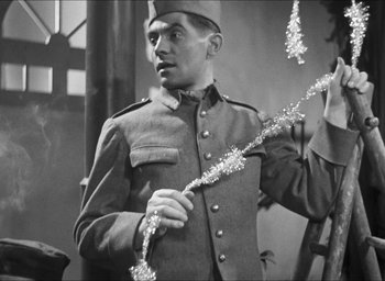 Movie still from “The Grand Illusion” (1937), directed by Jean Renoir – An old photo of a man in a military uniform holding tinsel; Medium shot, Low angle