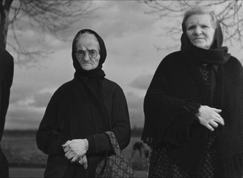 Movie still from “The Grand Illusion” (1937), directed by Jean Renoir – Two older women standing next to each other in front of trees; Medium shot, Low angle