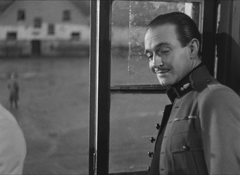 Movie still from “The Grand Illusion” (1937), directed by Jean Renoir – A black and white photo of a man looking out of a window; Close Up shot, Over the shoulder angle