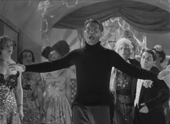 Movie still from “The Grand Illusion” (1937), directed by Jean Renoir – A man in a black sweater is singing; Medium shot, Low angle