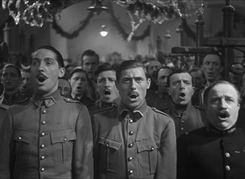 Movie still from “The Grand Illusion” (1937), directed by Jean Renoir – Black and white photograph of men in military uniforms singing; Medium shot, Low angle