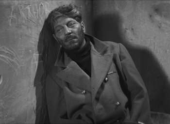 Movie still from “The Grand Illusion” (1937), directed by Jean Renoir – Black and white photograph of a man wearing a coat; Medium shot, High angle