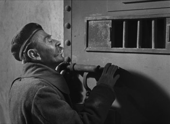 Movie still from “The Grand Illusion” (1937), directed by Jean Renoir – An old black and white photo of a man leaning against a window; Medium shot, Low angle