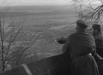 Movie still from “The Grand Illusion” (1937), directed by Jean Renoir – A man standing on top of a hill looking at a valley; Wide shot, High angle