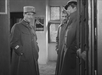 Movie still from “The Grand Illusion” (1937), directed by Jean Renoir – A group of men standing next to each other in a room; Medium shot, Over the shoulder angle