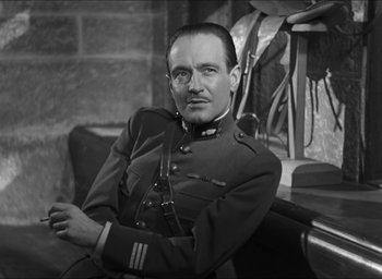 Movie still from “The Grand Illusion” (1937), directed by Jean Renoir – A man in a military uniform sitting in a chair; Medium shot, Low angle