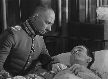 Movie still from “The Grand Illusion” (1937), directed by Jean Renoir – An old photo of a man laying in a hospital bed; Medium shot, Over the shoulder angle