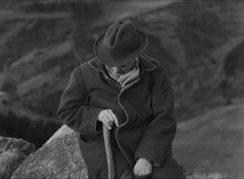 Movie still from “The Grand Illusion” (1937), directed by Jean Renoir – An older man in a hat and coat holding a cane; Medium shot, High angle