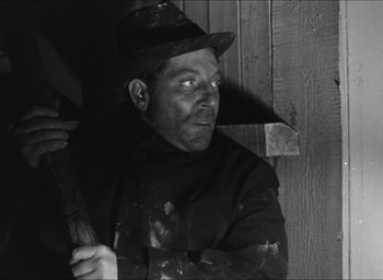 Movie still from “The Grand Illusion” (1937), directed by Jean Renoir – A black and white photo of a man holding an umbrella; Medium shot, Low angle