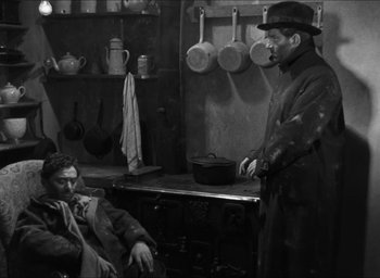 Movie still from “The Grand Illusion” (1937), directed by Jean Renoir – A man in a hat is standing next to a man in a coat; Medium shot, High angle