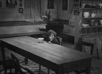 Movie still from “The Grand Illusion” (1937), directed by Jean Renoir – A little girl sitting at a table in a room; Wide shot, High angle