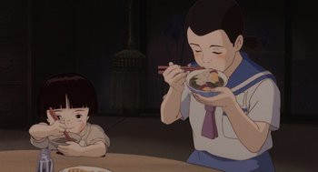 Movie still from “Grave of the Fireflies” (1988), directed by Isao Takahata – A boy and a girl are eating a bowl of food; Medium shot, High angle