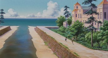 Two people walking on a beach near a house