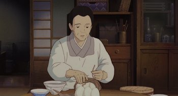 Movie still from “Grave of the Fireflies” (1988), directed by Isao Takahata – An animated man is making a bowl of food; Medium shot, Low angle