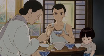 Movie still from “Grave of the Fireflies” (1988), directed by Isao Takahata – Two people sitting at a table with bowls of food; Medium shot, High angle