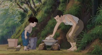 Movie still from “Grave of the Fireflies” (1988), directed by Isao Takahata – A man and a boy washing dishes in a bowl; Wide shot, Low angle
