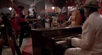 Movie still from “Great Balls of Fire!” (1989), directed by Jim McBride – A group of people in a room with a piano; Wide shot, High angle