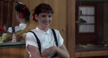 Movie still from “Great Balls of Fire!” (1989), directed by Jim McBride – A young woman in a white shirt and black suspenders smiling; Medium shot, Over the shoulder angle