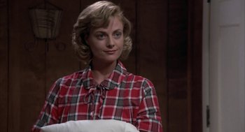 Movie still from “Great Balls of Fire!” (1989), directed by Jim McBride – A woman in a red and white plaid shirt holding a pillow; Close Up shot, Over the shoulder angle