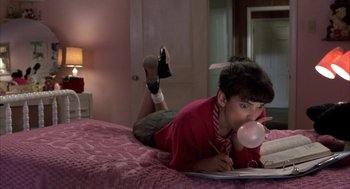 Movie still from “Great Balls of Fire!” (1989), directed by Jim McBride – A person laying on a bed with a pink blanket; Medium shot, High angle
