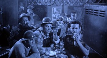 Movie still from “Great Balls of Fire!” (1989), directed by Jim McBride – A group of men sitting at a table with food; Medium shot, High angle