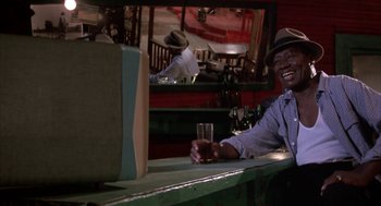 Movie still from “Great Balls of Fire!” (1989), directed by Jim McBride – A man sitting at a bar holding a glass of wine; Medium shot, Low angle