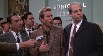 Movie still from “Great Balls of Fire!” (1989), directed by Jim McBride – A group of men standing next to each other in a room; Medium shot, Over the shoulder angle