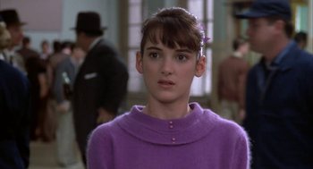 Movie still from “Great Balls of Fire!” (1989), directed by Jim McBride – A woman in a purple sweater and a purple flower in her hair; Close Up shot, Over the shoulder angle