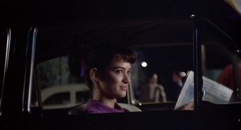Movie still from “Great Balls of Fire!” (1989), directed by Jim McBride – A woman sitting in the back seat of a car at night; Close Up shot, Over the shoulder angle
