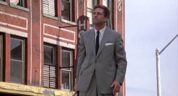 Movie still from “Great Balls of Fire!” (1989), directed by Jim McBride – A man in a suit and tie standing in front of a building; Wide shot, Low angle