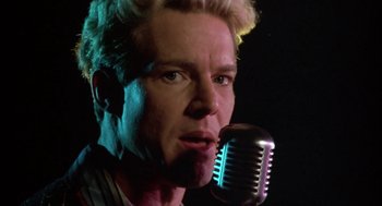 Movie still from “Great Balls of Fire!” (1989), directed by Jim McBride – A person holding a microphone; Close Up shot, Low angle