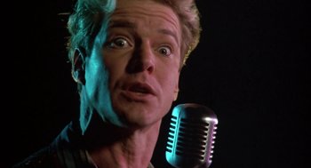 Movie still from “Great Balls of Fire!” (1989), directed by Jim McBride – A person with a microphone; Close Up shot, Low angle