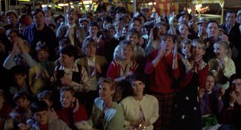 Movie still from “Great Balls of Fire!” (1989), directed by Jim McBride – A group of people sitting in a crowd at night; Wide shot, High angle