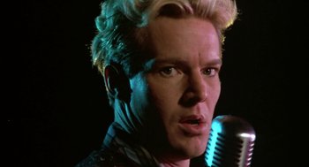 Movie still from “Great Balls of Fire!” (1989), directed by Jim McBride – A person holding a microphone; Close Up shot, Low angle