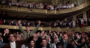 Movie still from “Great Balls of Fire!” (1989), directed by Jim McBride – A group of people in a large room with their hands in the air; Wide shot, High angle