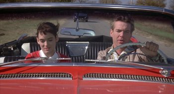 Movie still from “Great Balls of Fire!” (1989), directed by Jim McBride – A man and a boy in the back of an old car; Medium shot, Over the shoulder angle