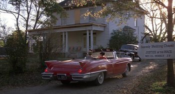 Movie still from “Great Balls of Fire!” (1989), directed by Jim McBride – An old car is parked on the side of the road; Extreme Wide shot, Low angle