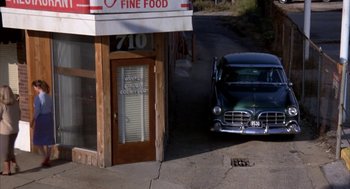 Movie still from “Great Balls of Fire!” (1989), directed by Jim McBride – An old car parked in front of a building; Extreme Wide shot, High angle