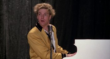 Movie still from “Great Balls of Fire!” (1989), directed by Jim McBride – A man in a yellow jacket standing next to a microphone; Close Up shot, Low angle