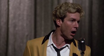 Movie still from “Great Balls of Fire!” (1989), directed by Jim McBride – A man in a yellow jacket is singing into a microphone; Close Up shot, Low angle