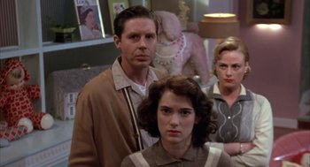 Movie still from “Great Balls of Fire!” (1989), directed by Jim McBride – A man and two women standing next to each other in a room; Medium shot, Over the shoulder angle