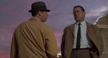 Movie still from “Great Balls of Fire!” (1989), directed by Jim McBride – Two men standing next to each other on a cloudy day; Medium shot, Low angle